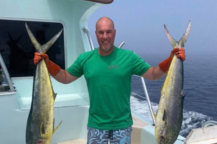 a man holding a fish on a boat