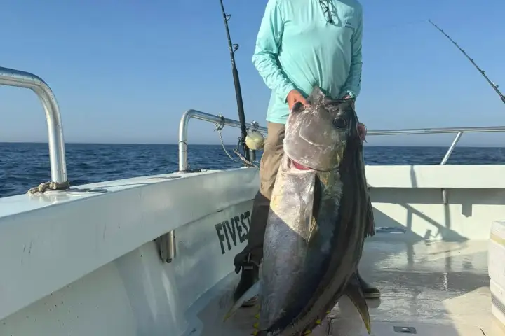 a man holding a fish on a boat