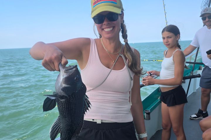 Woman holding a fish on a boat, with a girl and others in the background.