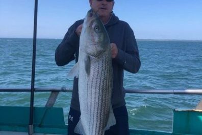 a man holding a fish on a boat in a body of water