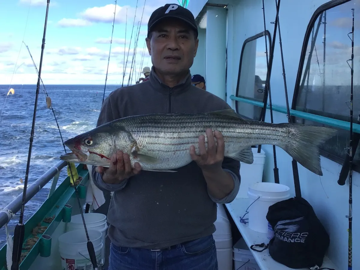 a man holding a fish on a boat in a body of water