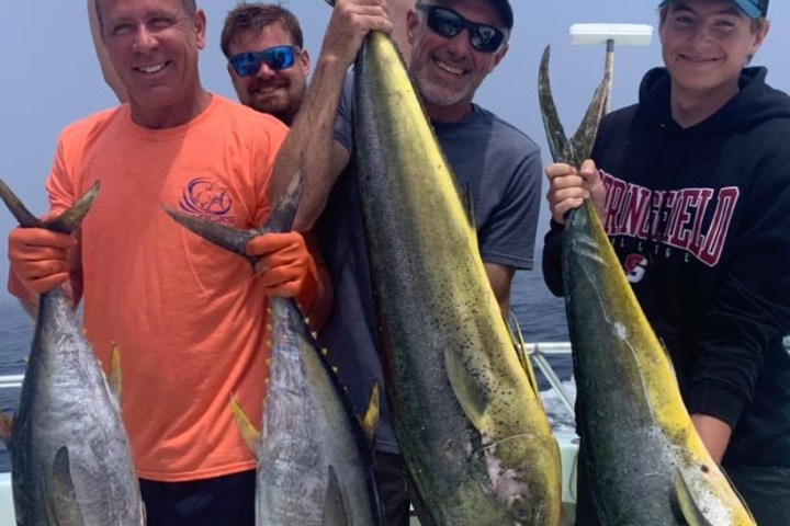 a group of people standing next to a man holding a fish