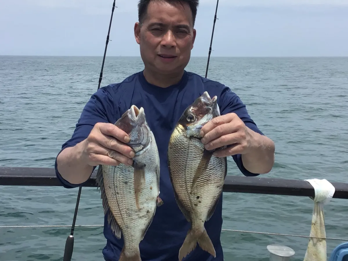 a person holding a fish on a boat in a body of water