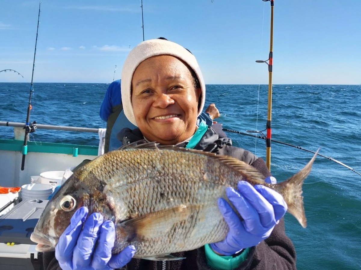 a person holding a fish on a boat in a body of water