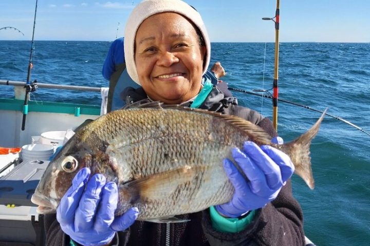 a person holding a fish on a boat in a body of water
