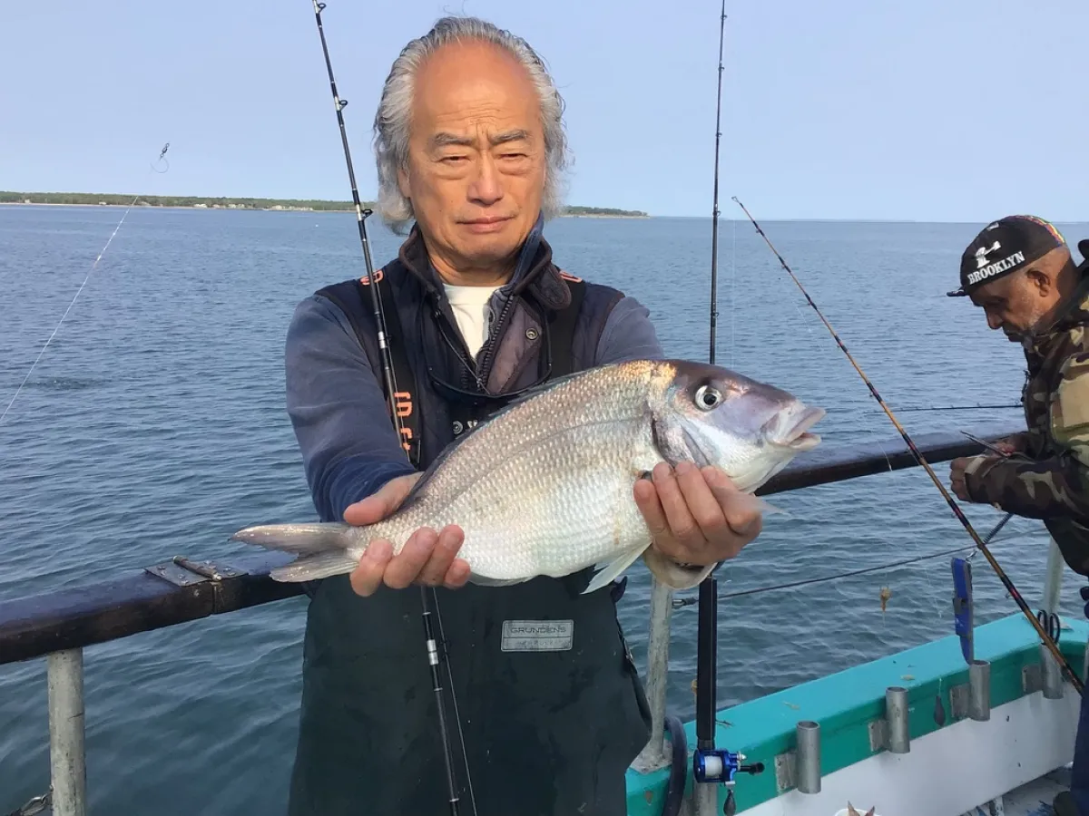 Li Bomin holding a fish on a boat in a body of water
