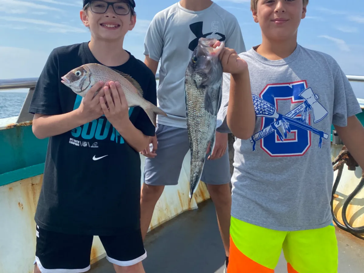 a group of people standing next to a person holding a fish