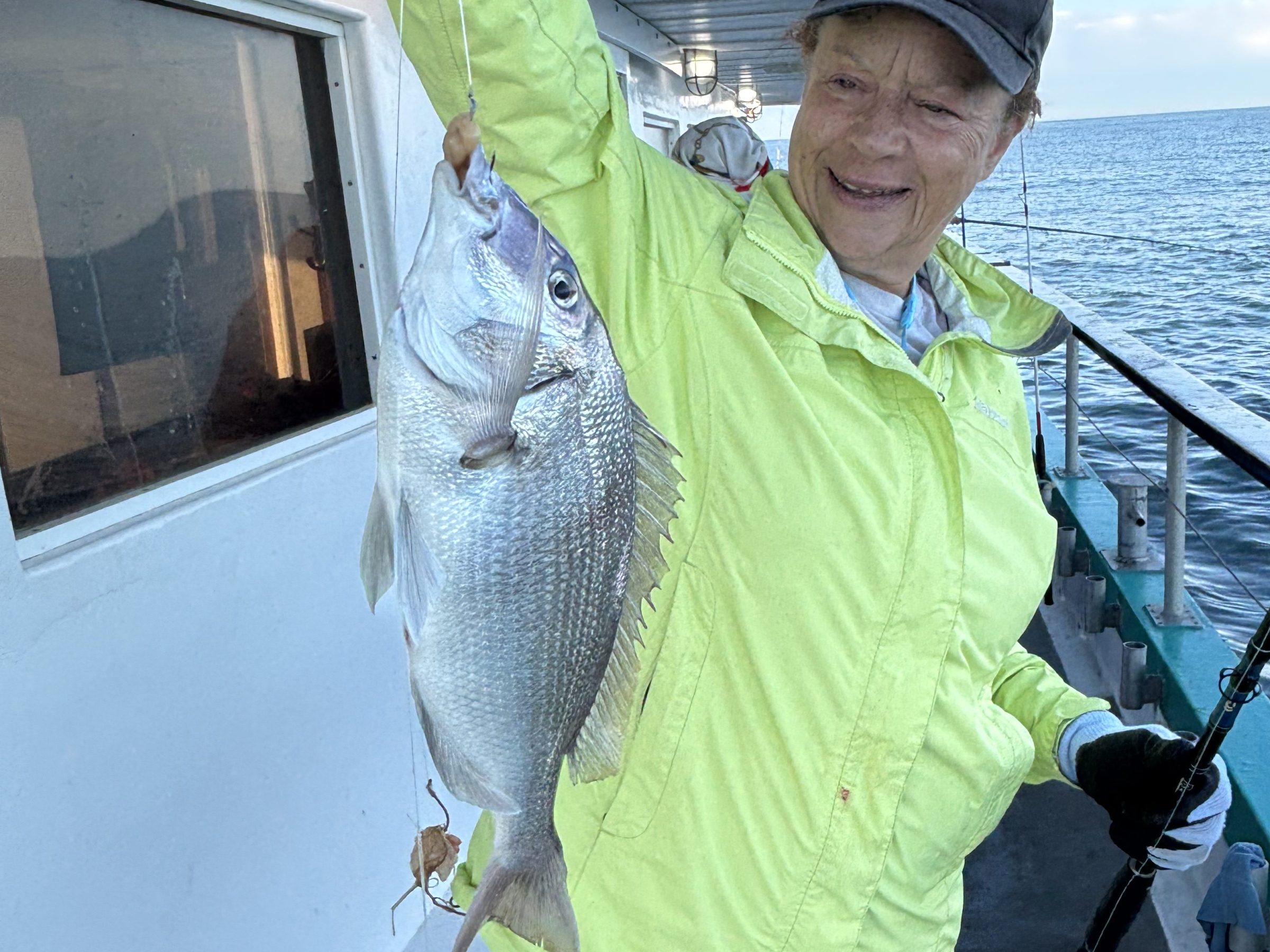 Person on a boat holding a large fish with fishing rod.