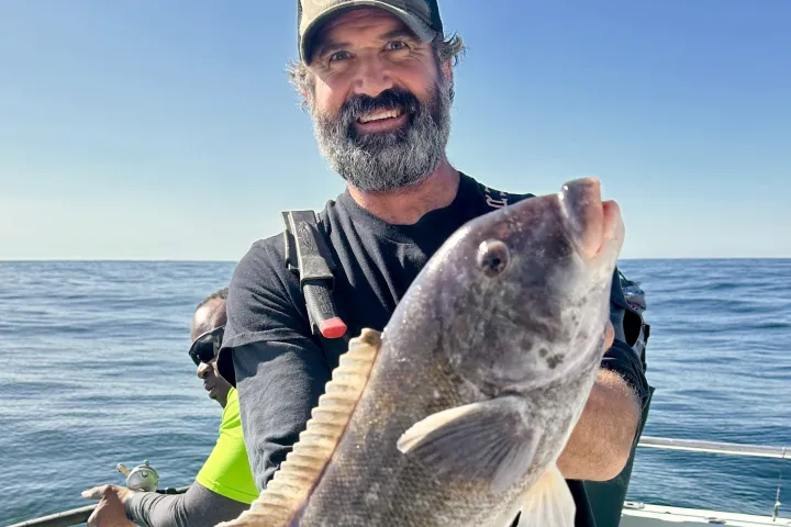 a man holding a fish on a boat in the water