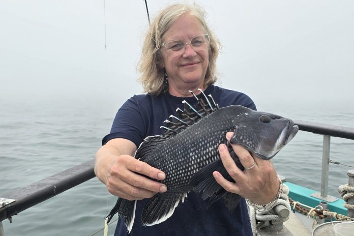 a person standing in front of a boat next to a body of water