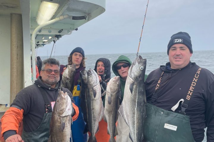 a group of people standing in front of a military man holding a fish