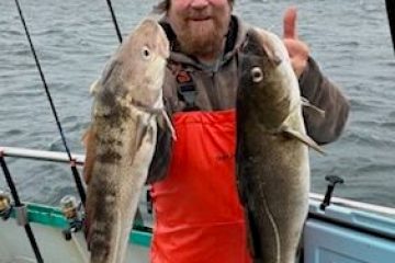 a man holding a fish on a boat in the water