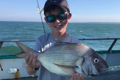 a man holding a fish on a boat in the water