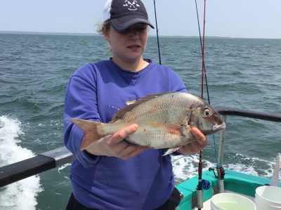 a person holding a fish on a boat in a body of water