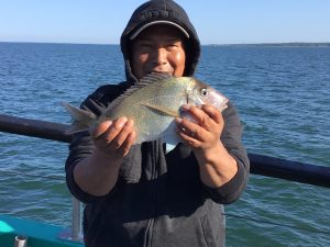 a person holding a fish on a boat in a body of water