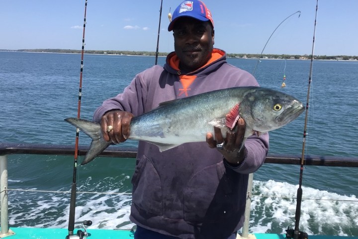 a man holding a fish on a boat in a body of water