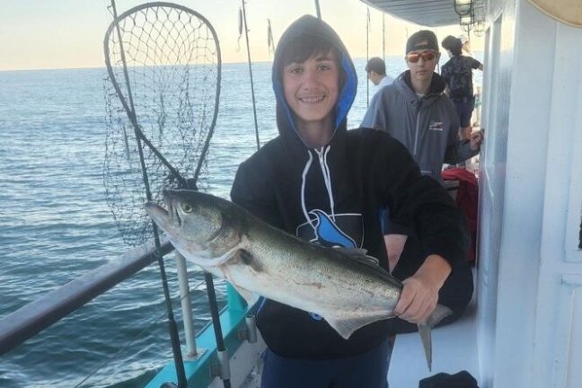 a man holding a fish on a boat