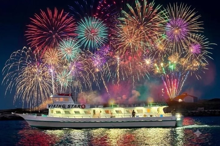 A boat on water with colorful fireworks lighting up the night sky.