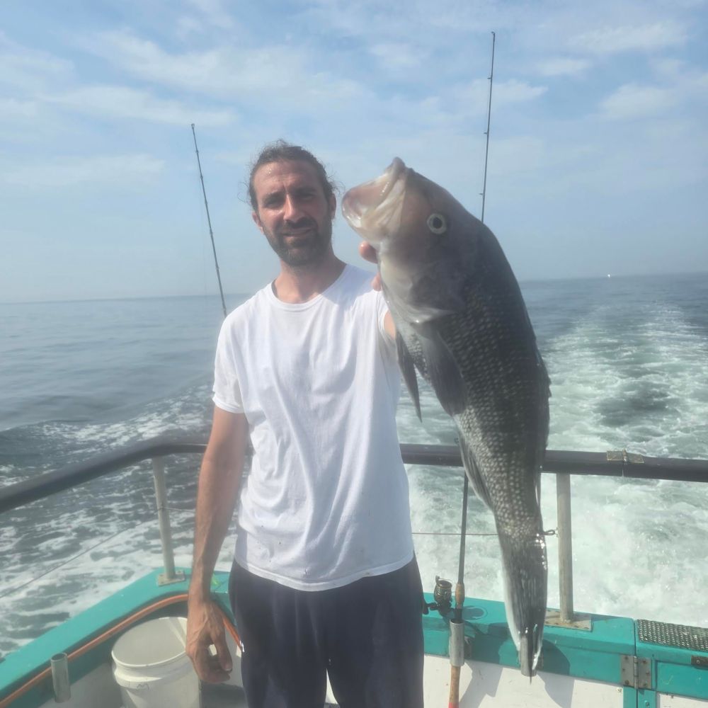 a man holding a fish on a boat in a body of water