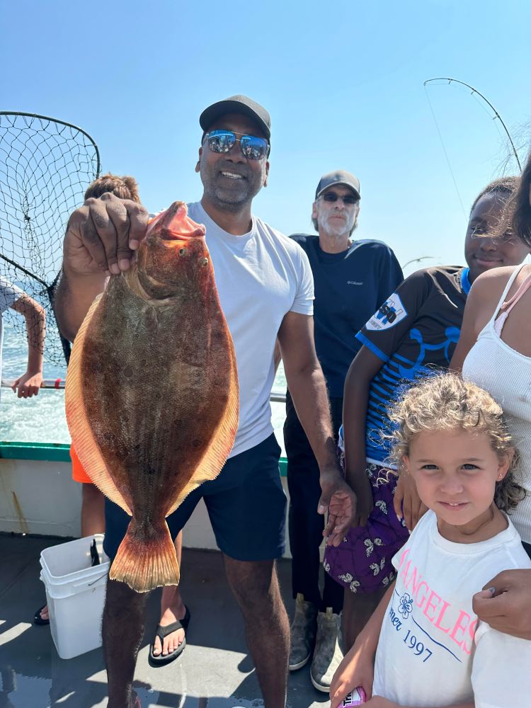 a group of people standing next to a man holding a fish